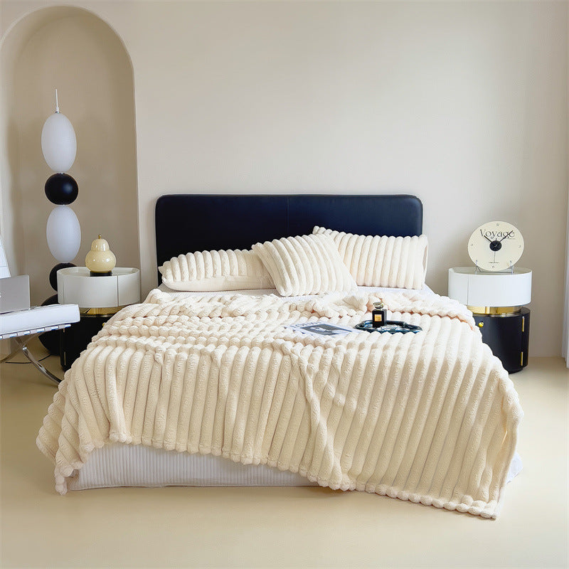 Plaid en peluche vert replié au pied d'un lit