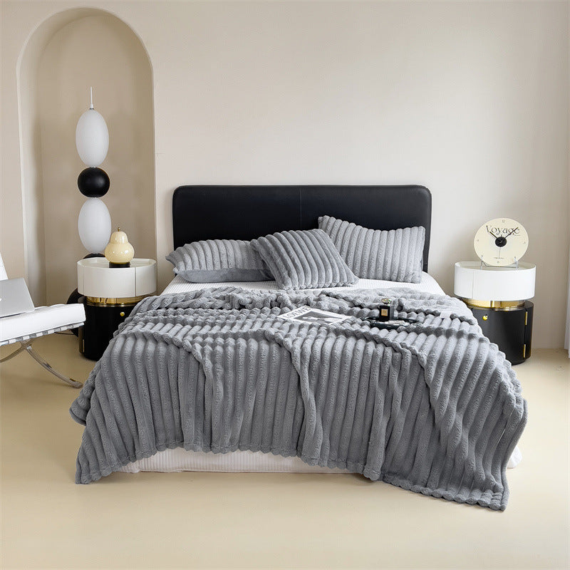 Plaid en peluche marron posé sur une literie claire