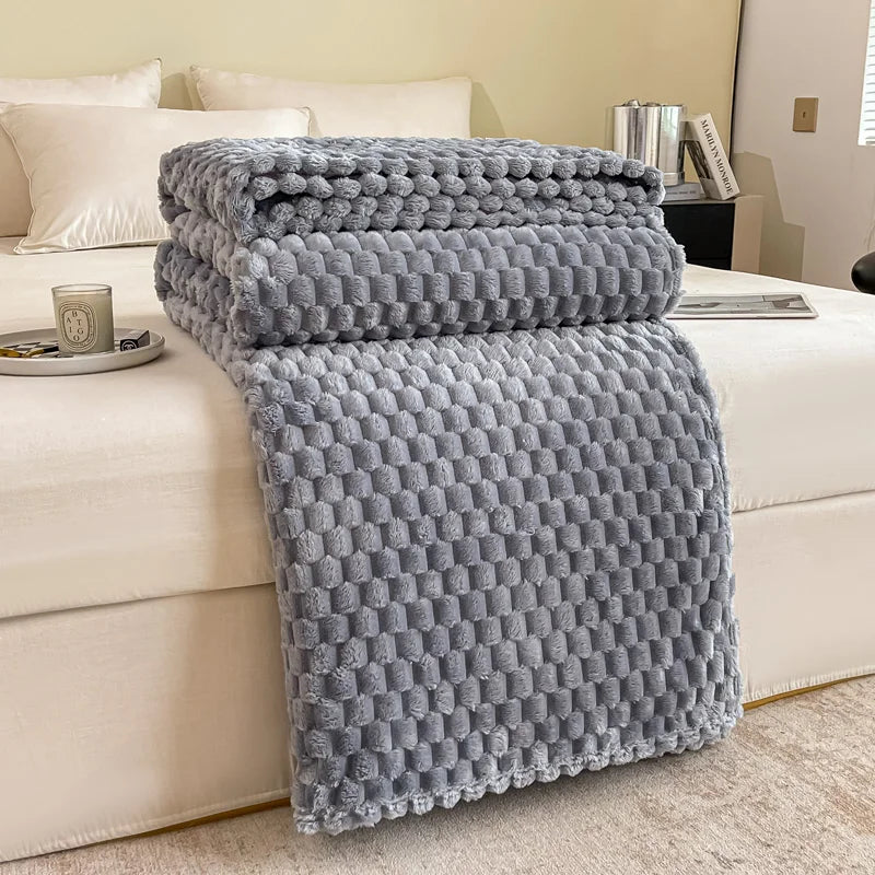 Plaid en velours à carreaux coloris gris clair posé sur un canapé