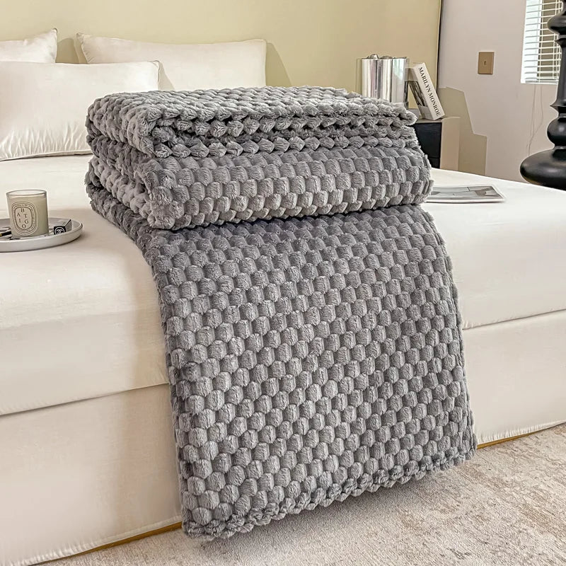 Plaid en velours à carreaux coloris gris posé sur un canapé