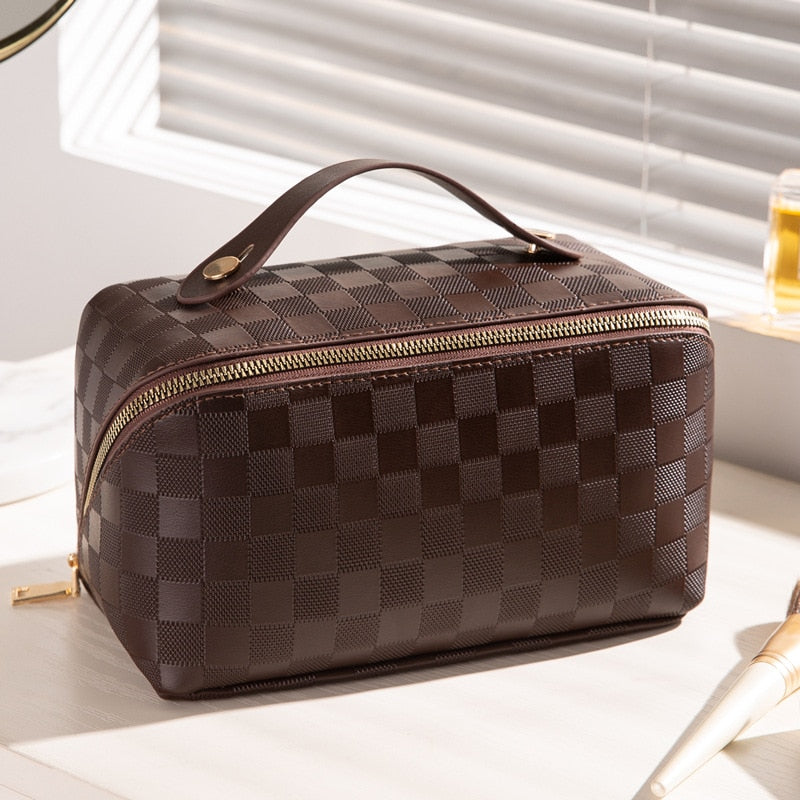 Trousse de maquillage à motif à carreaux tenue par sa poignée