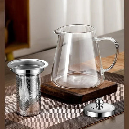 Théière en verre posée près d'une bouilloire et de tasses