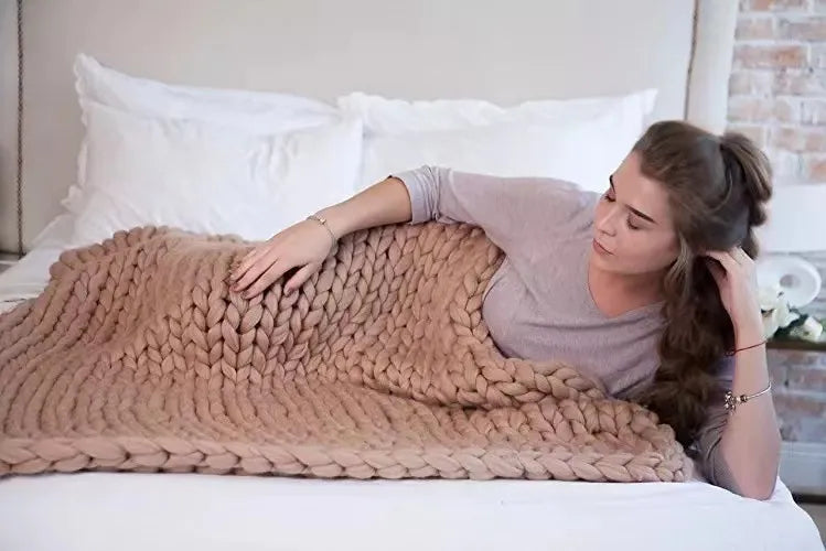 Plaid en grosse maille étalé sur un tapis clair