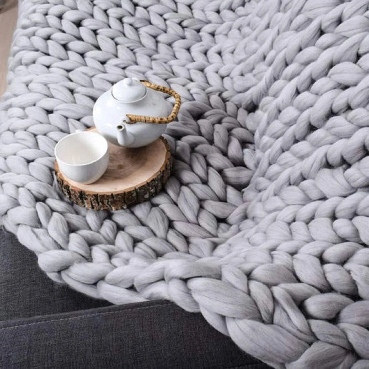 Plaid en grosse maille plié en trois sur un pouf