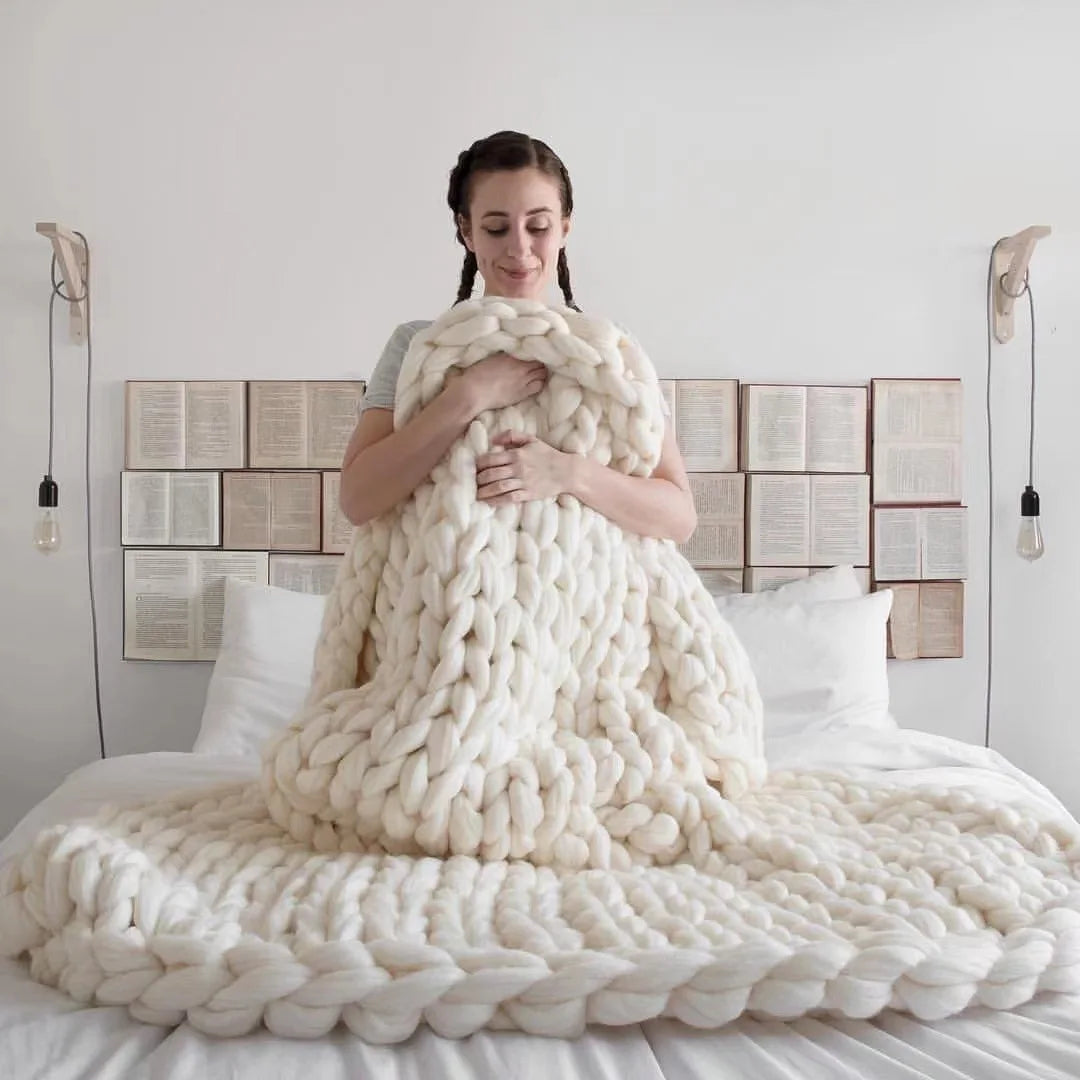 Plaid en grosse maille au pied d'un lit dans une chambre