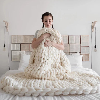 Plaid en grosse maille au pied d'un lit dans une chambre