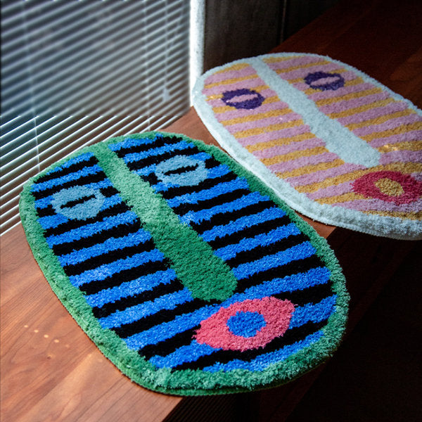 Tapis de bain en velours au motif de visage abstrait posé devant une douche
