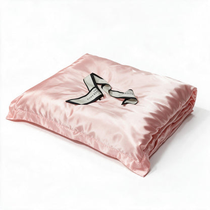 Parure de lit en pure soie rose sur un lit double.