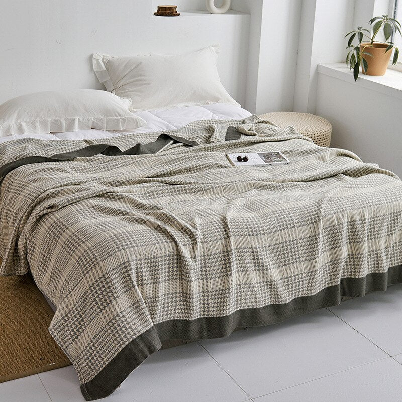 Plaid japonais en coton, motif dent-de-loup gris, posé sur un lit.