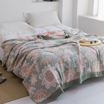 Plaid japonais en coton, motif tournesols vert et rose, posé sur un lit.