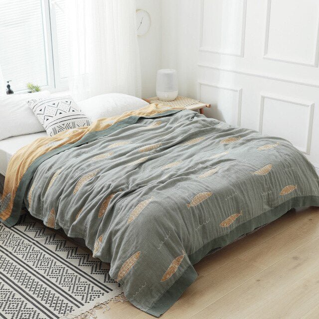 Plaid japonais en coton, motif poissons gris, posé sur un lit.