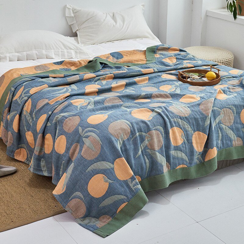 Plaid japonais en coton, motif feuillage bleu et orange, posé sur un lit.