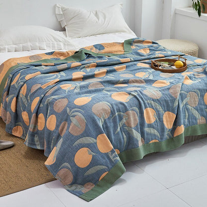 Plaid japonais en coton, motif feuillage bleu et orange, posé sur un lit.
