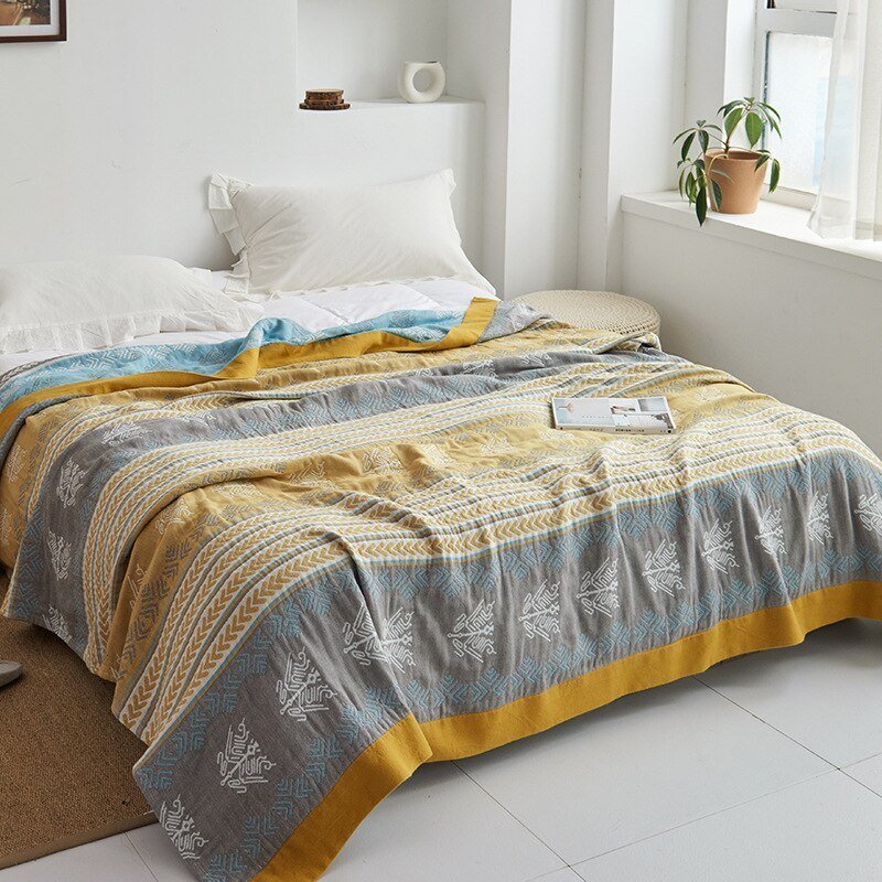 Plaid japonais en coton, motif graphique bleu et doré, posé sur un lit.