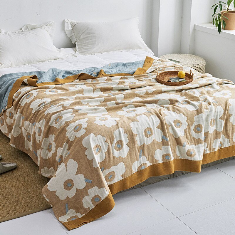 Plaid japonais en coton, motif fleurs doré et blanc, posé sur un lit.
