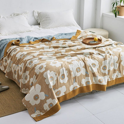Plaid japonais en coton, motif fleurs doré et blanc, posé sur un lit.