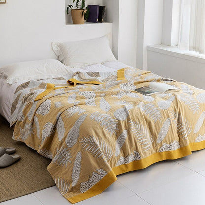 Plaid japonais en coton, motif feuillage jaune, posé sur un lit.