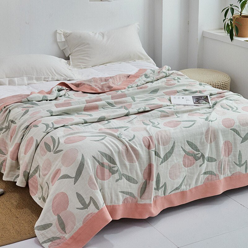Plaid japonais en coton, motif feuillage rose et blanc, posé sur un lit.