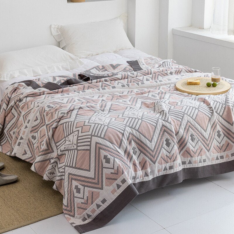 Plaid japonais en coton, motif aztèque rose, posé sur un lit.