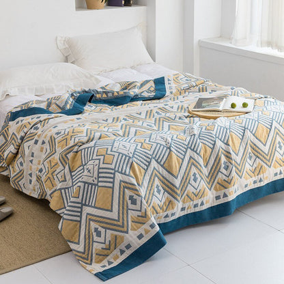 Plaid japonais en coton, motif aztèque jaune et bleu, posé sur un lit.